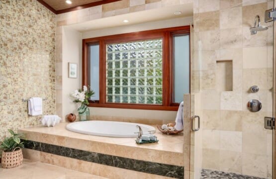 Spacious primary bathroom at Hale Mele with a soaking tub, walk-in rain shower, and elegant stone finishes in Mauna Lani, Hawaiʻi.
