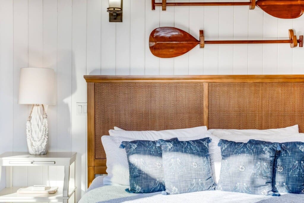 Guest bedroom at Hale Mele featuring a woven headboard, handcrafted koa paddles, and tropical-inspired décor in Mauna Lani.
