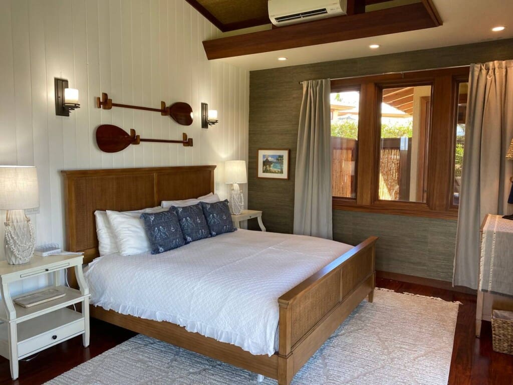 Bedroom 3 at Hale Mele featuring a king bed, tropical-inspired décor, hardwood floors, and large windows in a luxury vacation rental in Mauna Lani on the Big Island of Hawaiʻi.