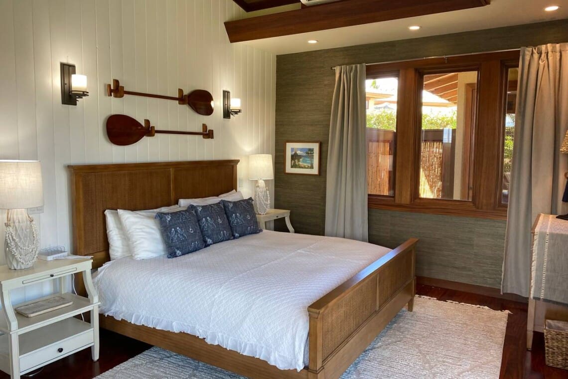 Bedroom 3 at Hale Mele featuring a king bed, tropical-inspired décor, hardwood floors, and large windows in a luxury vacation rental in Mauna Lani on the Big Island of Hawaiʻi.