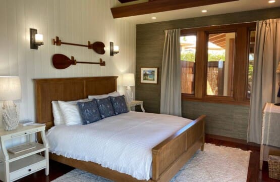 Bedroom 3 at Hale Mele featuring a king bed, tropical-inspired décor, hardwood floors, and large windows in a luxury vacation rental in Mauna Lani on the Big Island of Hawaiʻi.