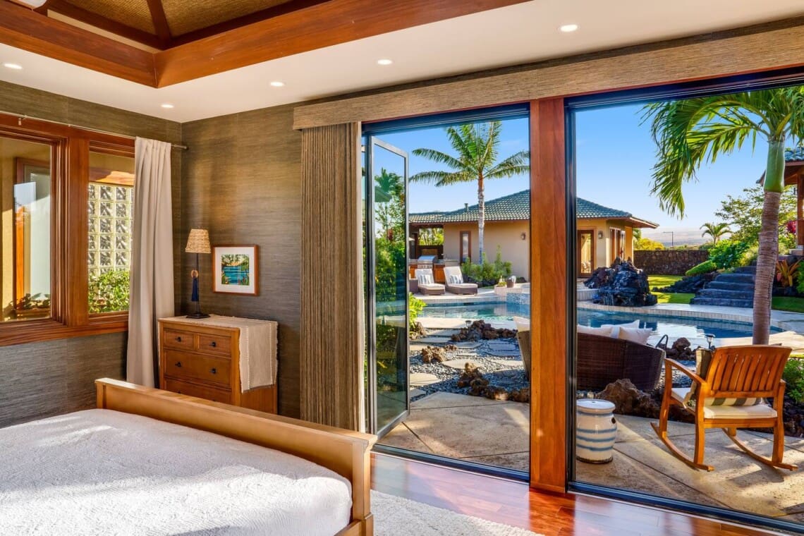 Bedroom 3 at Hale Mele with direct access to a private patio overlooking the pool and tropical gardens in Mauna Lani, Hawaiʻi.