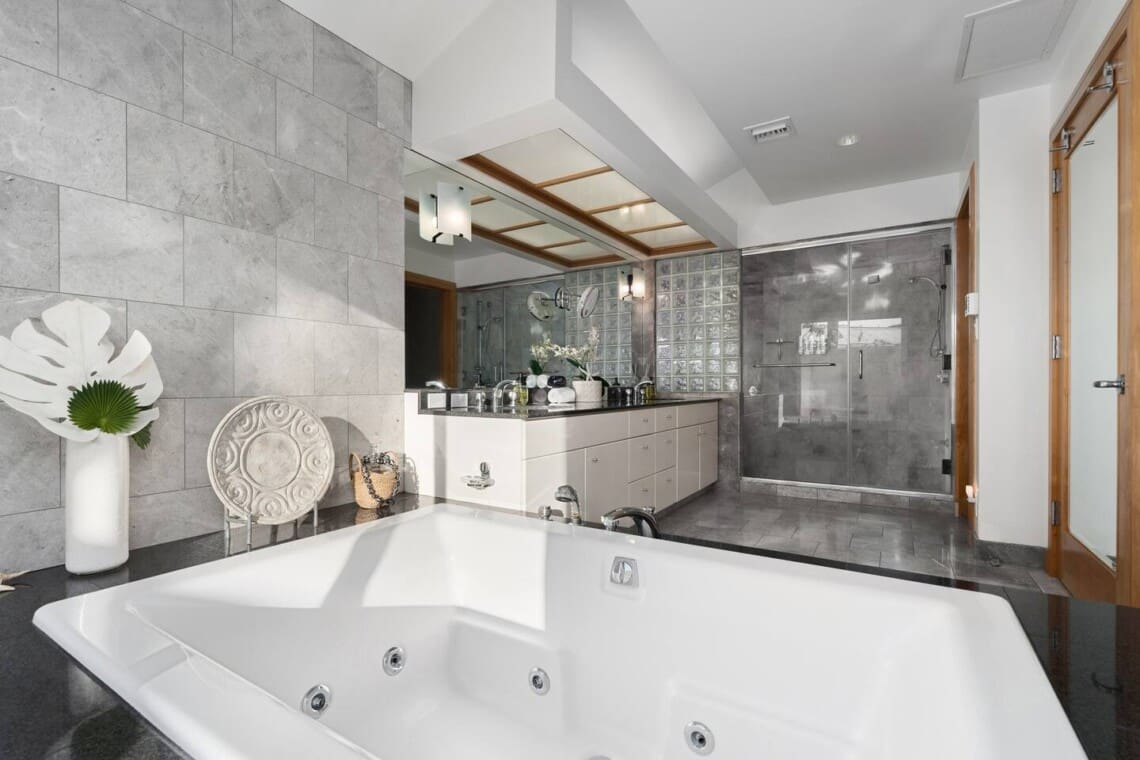 Luxury primary bathroom with jetted soaking tub, walk-in glass shower, and dual vanity at Hale Mele in Mauna Lani.
