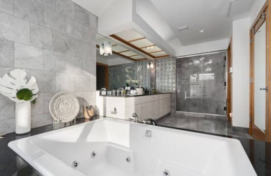 Luxury primary bathroom with jetted soaking tub, walk-in glass shower, and dual vanity at Hale Mele in Mauna Lani.