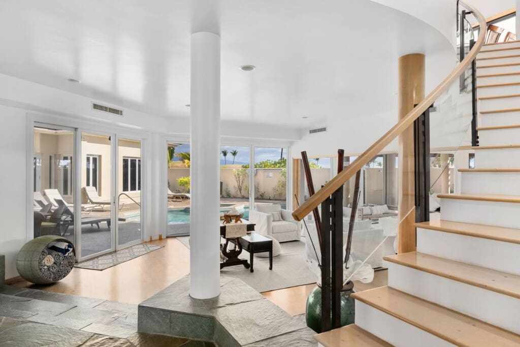 Bright entryway with staircase, living room, and sliding doors opening to the private pool at Hale Mele in Mauna Lani.