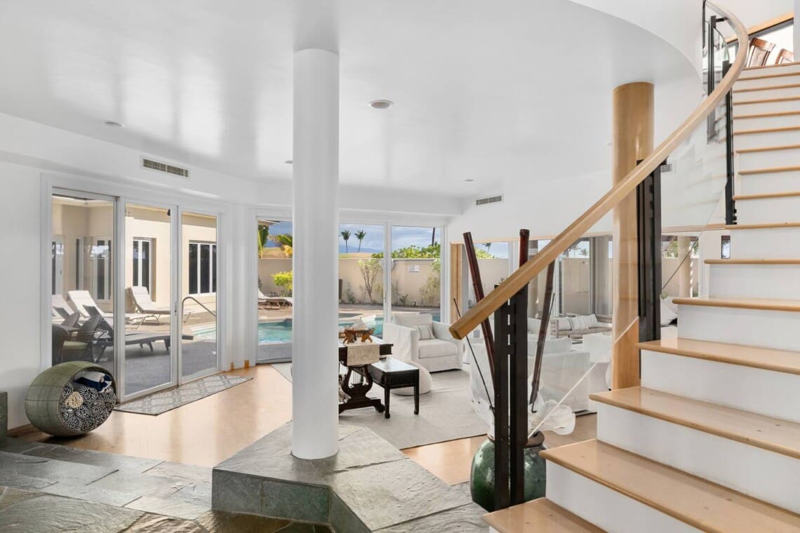 Bright entryway with staircase, living room, and sliding doors opening to the private pool at Hale Mele in Mauna Lani.