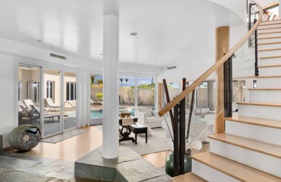 Bright entryway with staircase, living room, and sliding doors opening to the private pool at Hale Mele in Mauna Lani.