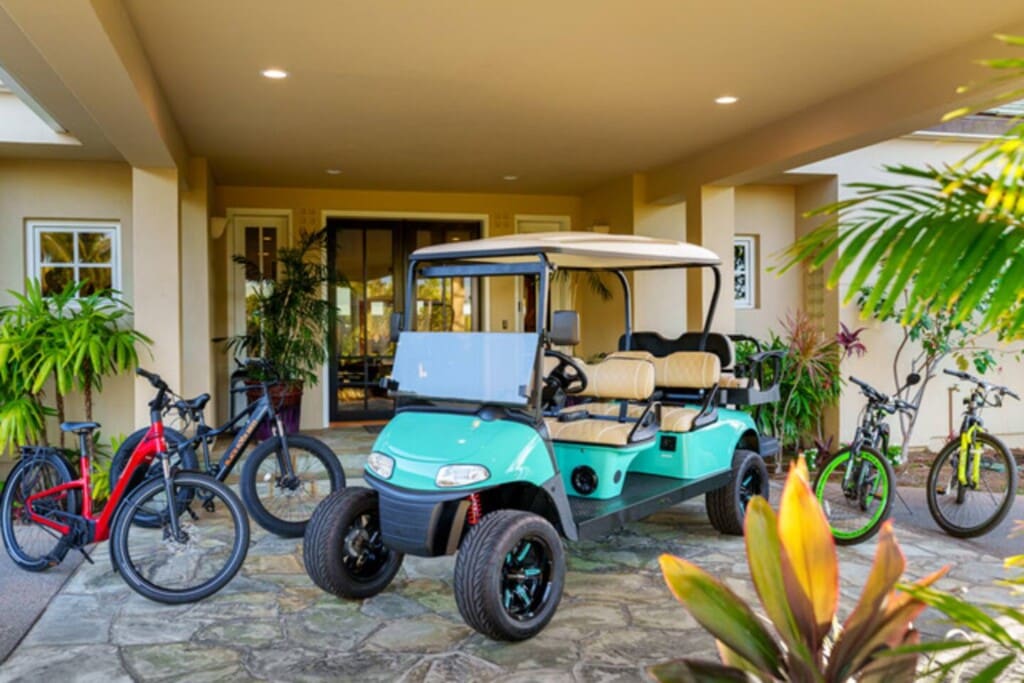 Golf cart and bicycles parked beneath the covered entrance of Hale Mele in Mauna Lani.