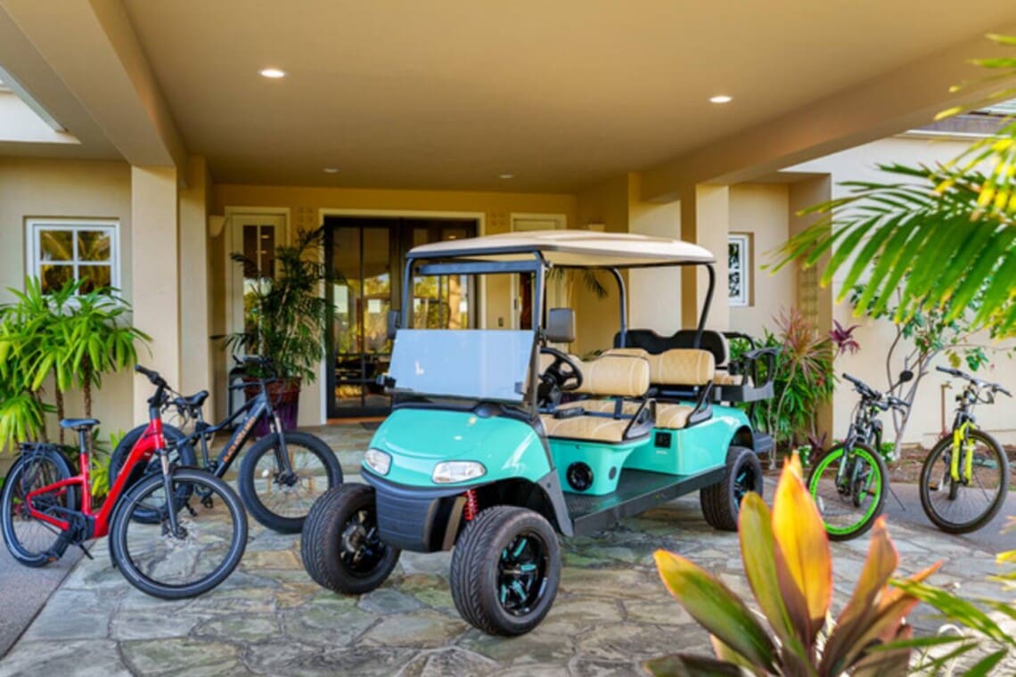 Golf cart and bicycles parked beneath the covered entrance of Hale Mele in Mauna Lani.