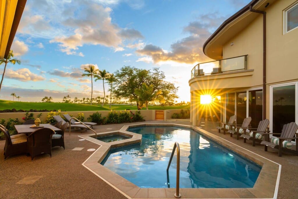 Private pool and spa with lounge chairs, outdoor dining area, and golf course views at sunset.