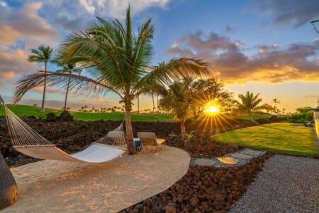 Private hammock garden with palm trees, sandy seating area, lava rock landscaping, and sunset at Hale Mele.