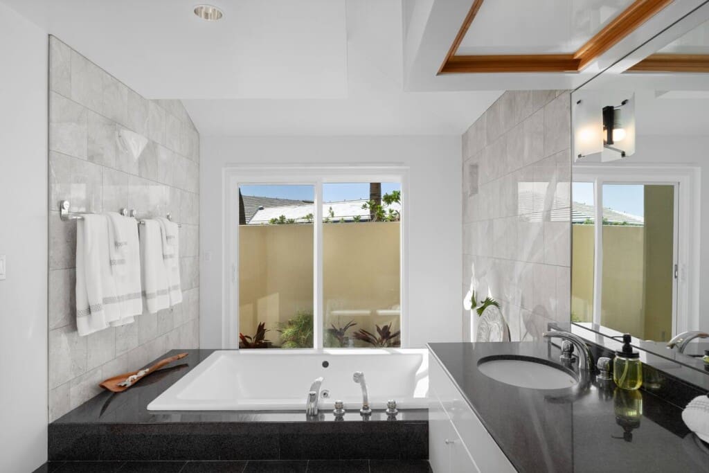 Primary bathroom with soaking tub, dual vanity, and spa-inspired design at Hale Mele luxury vacation rental in Mauna Lani.