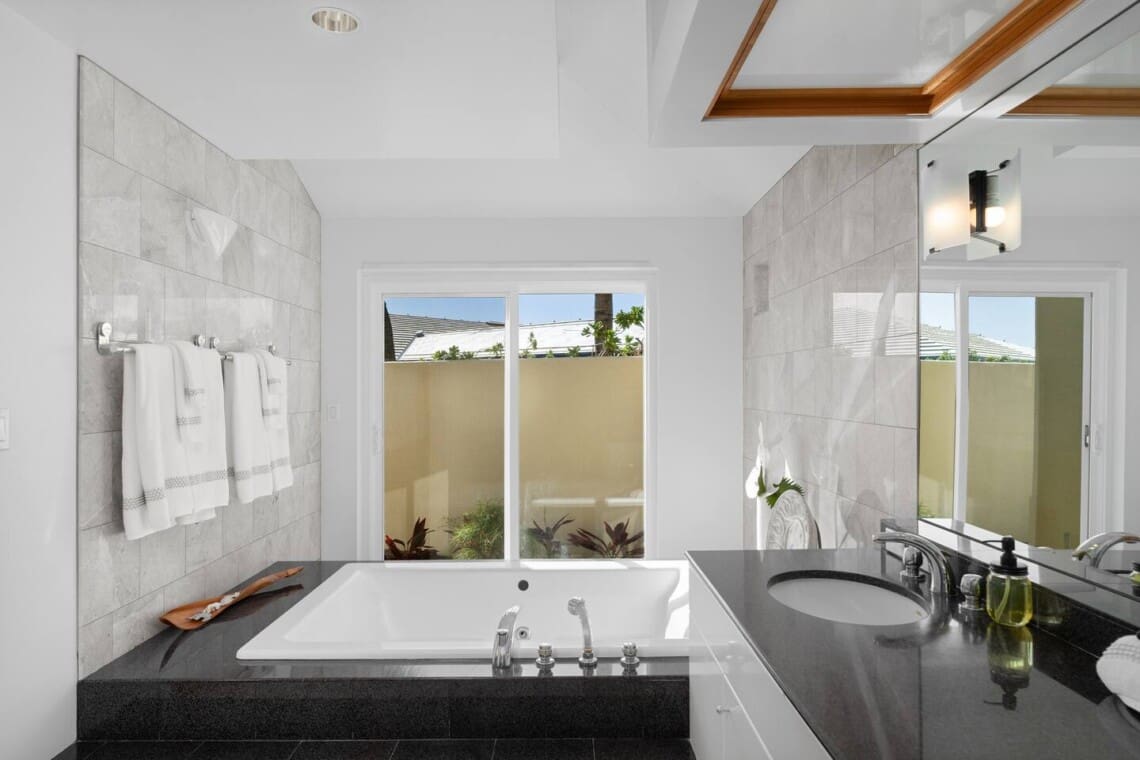 Primary bathroom with soaking tub, dual vanity, and spa-inspired design at Hale Mele luxury vacation rental in Mauna Lani.