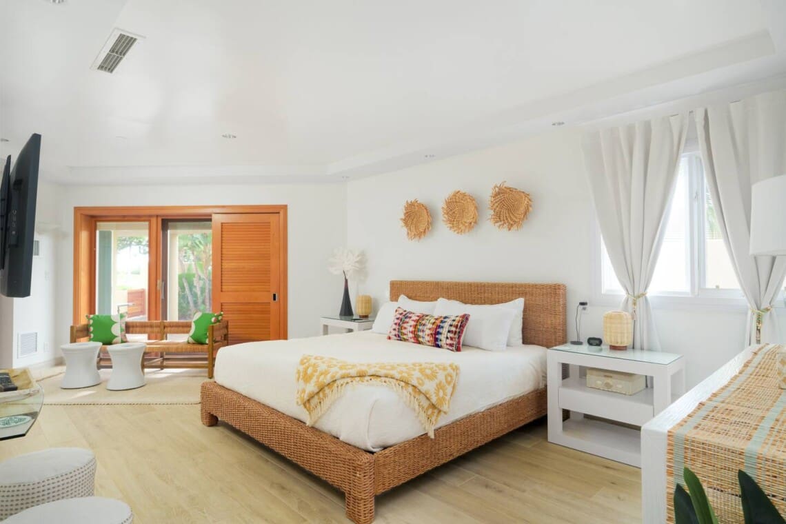 Spacious primary king bedroom at Hale Mele luxury vacation rental in Mauna Lani with woven furnishings and tropical-inspired decor.