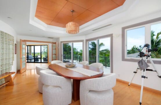 A bright secondary dining or meeting room with an oval wooden table, upholstered chairs, and a telescope near a window.