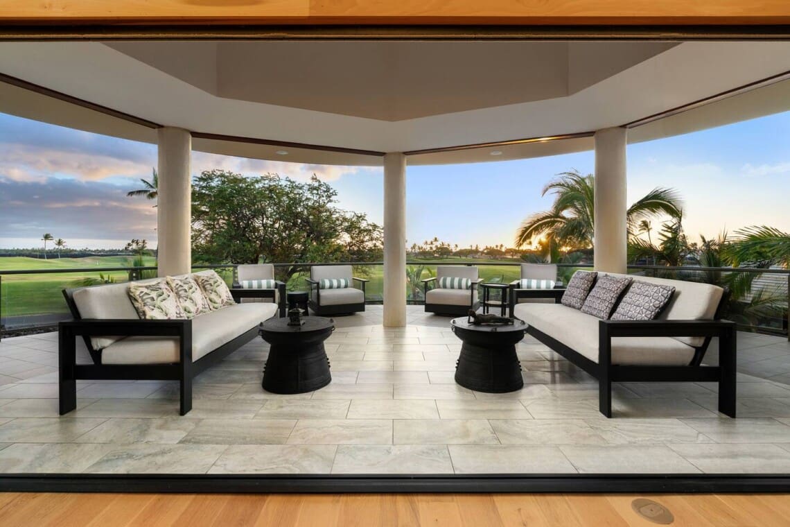 Covered outdoor lanai with lounge seating overlooking the Mauna Lani golf course at sunset.