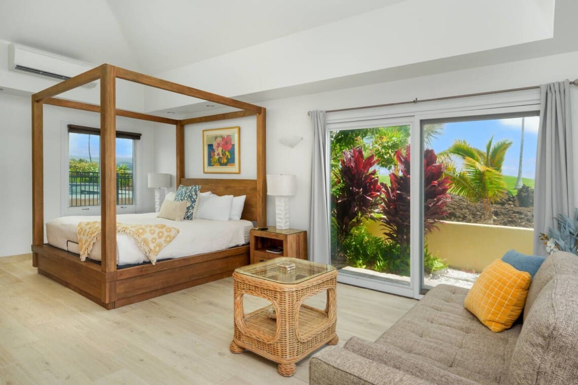 Spacious guest bedroom at Hale Mele featuring a four-poster king bed, tropical décor, and private lanai access in Mauna Lani.