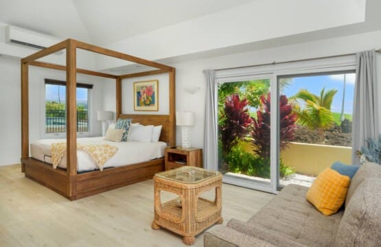 Spacious guest bedroom at Hale Mele featuring a four-poster king bed, tropical décor, and private lanai access in Mauna Lani.