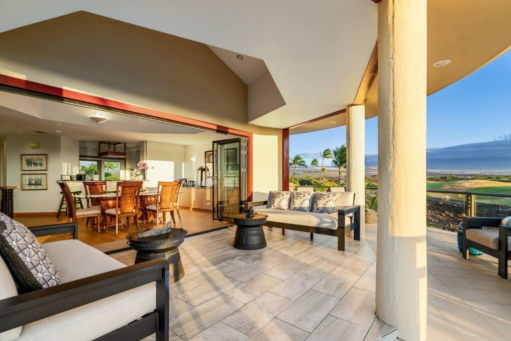 Covered lanai with lounge seating, open dining area, and golf course views at Hale Mele luxury vacation rental in Mauna Lani.