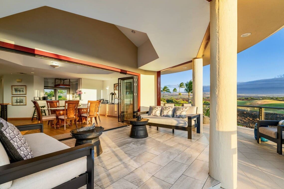Covered lanai with lounge seating, open dining area, and golf course views at Hale Mele luxury vacation rental in Mauna Lani.